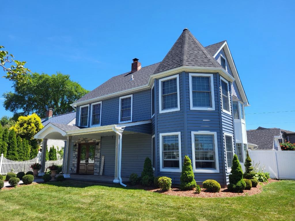 Completed gray siding, roofing, windows, and entry renovation on a two-story Long Island home